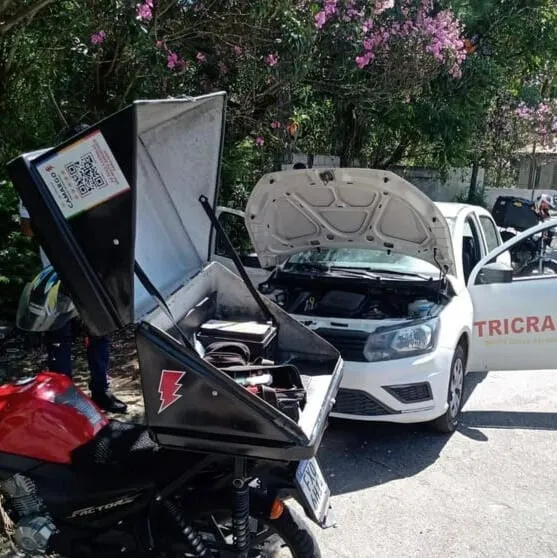 Baú da moto aberto com as ferramentas, durante um socorro de bateria na rua